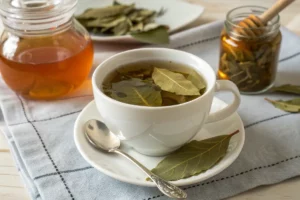 Xícara de chá de louro com folhas de louro fresco ao lado, bebida quente e aromática.