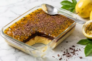Travessa de cerâmica branca com trufado de maracujá finalizado, mostrando camadas de creme amarelo-creme, ganache de chocolate meio amargo e calda brilhante de maracujá com sementes, com porção retirada revelando as camadas internas.