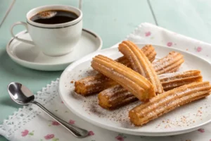 Churros crocantes dourados cobertos de canela e açúcar sobre tábua rústica com molho de chocolate ao lado