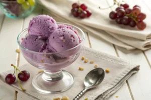 Sorvete de uva roxa cremoso com pedaços de fruta fresca, textura gelada servida em taça transparente com colher.​​